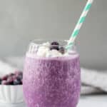 side view of keto berry smoothie in a glass with a straw