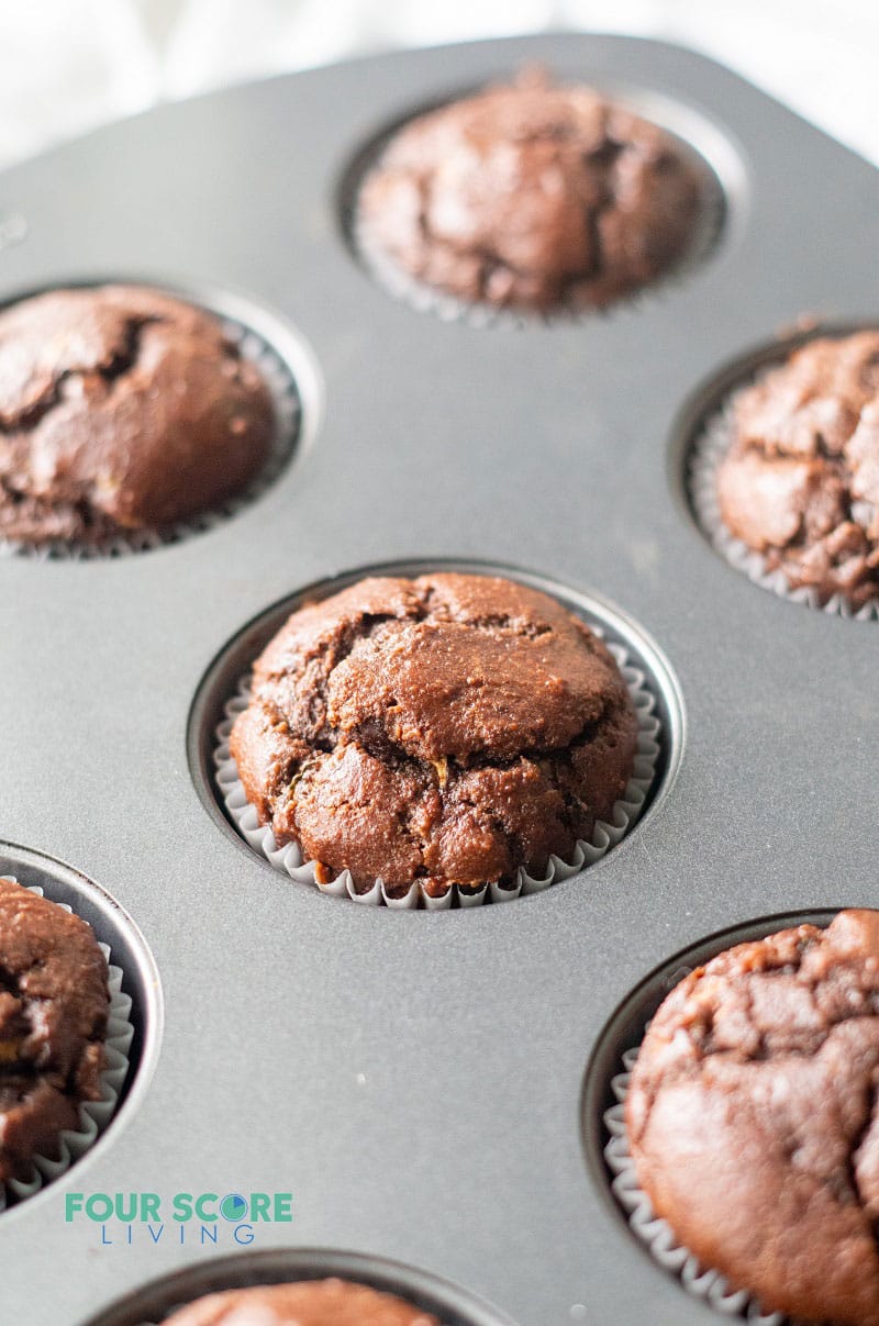 fresh baked chocolate zucchini muffins in a metal muffin pan.