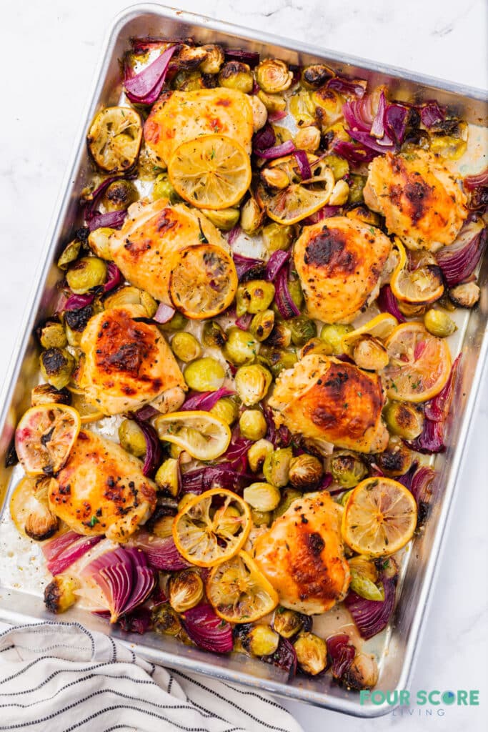 sheet pan chicken and brussels sprouts with sliced lemons and red onion