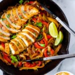 chicken and onions and peppers in a cast iron skillet
