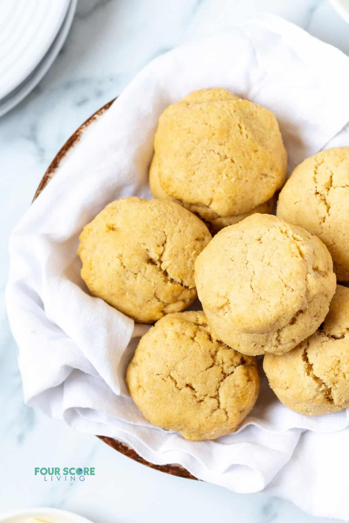 a bowl lined with a white tea towel filled with homemade biscuits