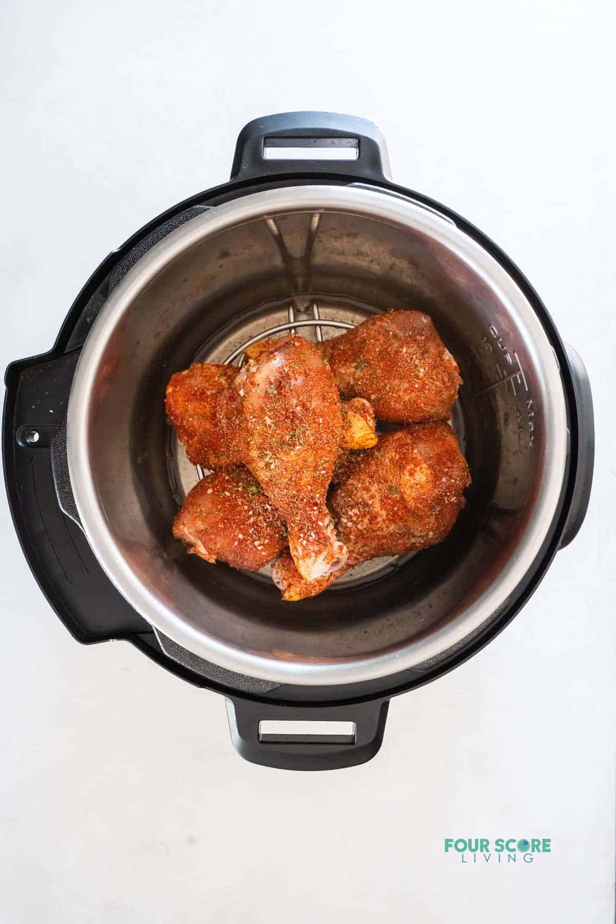 raw, seasoned chicken legs inside of an instant pot, viewed from above
