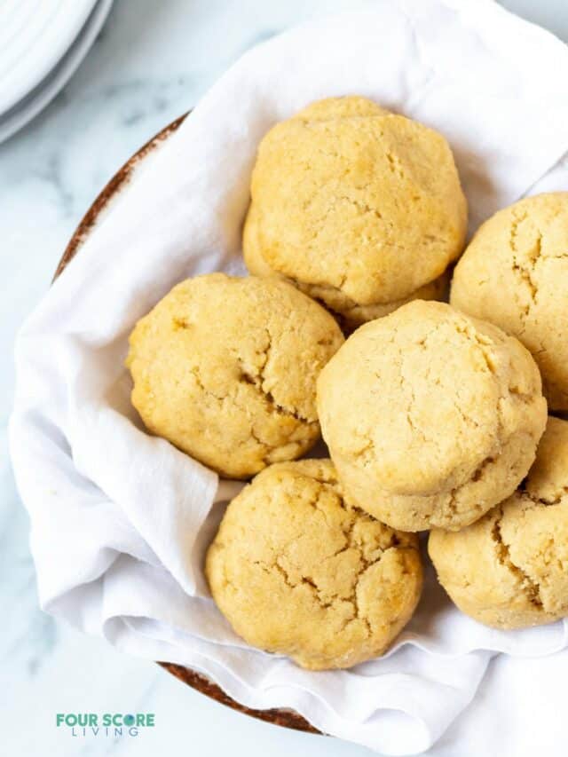 a bowl lined with a white tea towel filled with homemade almond flour biscuits