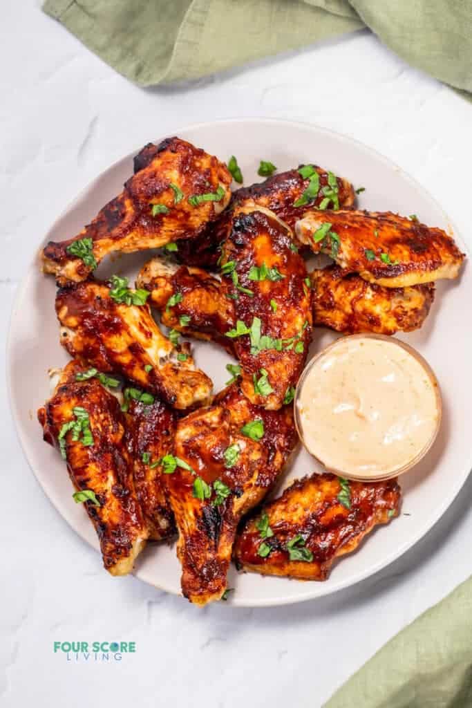 chicken wings on a white plat with sauce