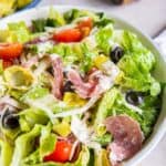 Photo of a large white bowl filled with Grinder Salad. There is a pepper grinder in the background.