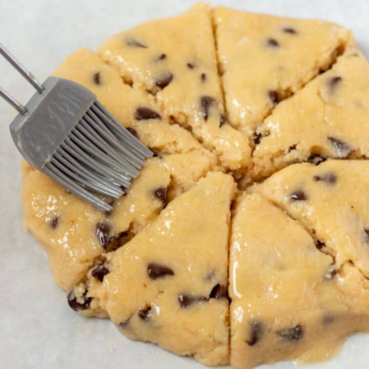 The formed and cut dough being brushed with melted butter before being baked.