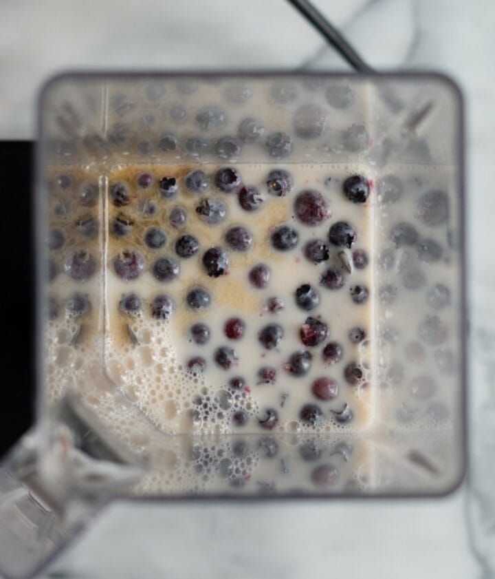 Blender containing almond milk, blueberries and protein powder.
