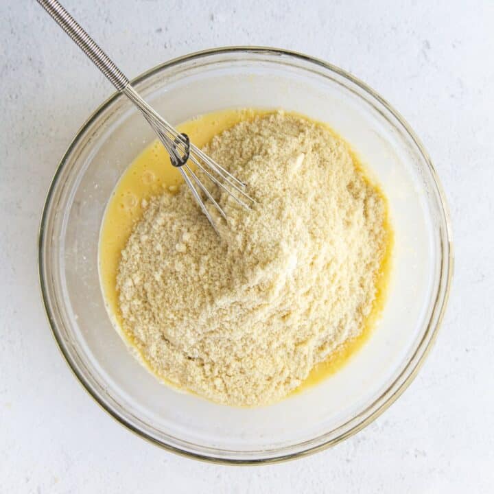 Glass bowl with dry cake ingredients being whisked into the wet ingredients.