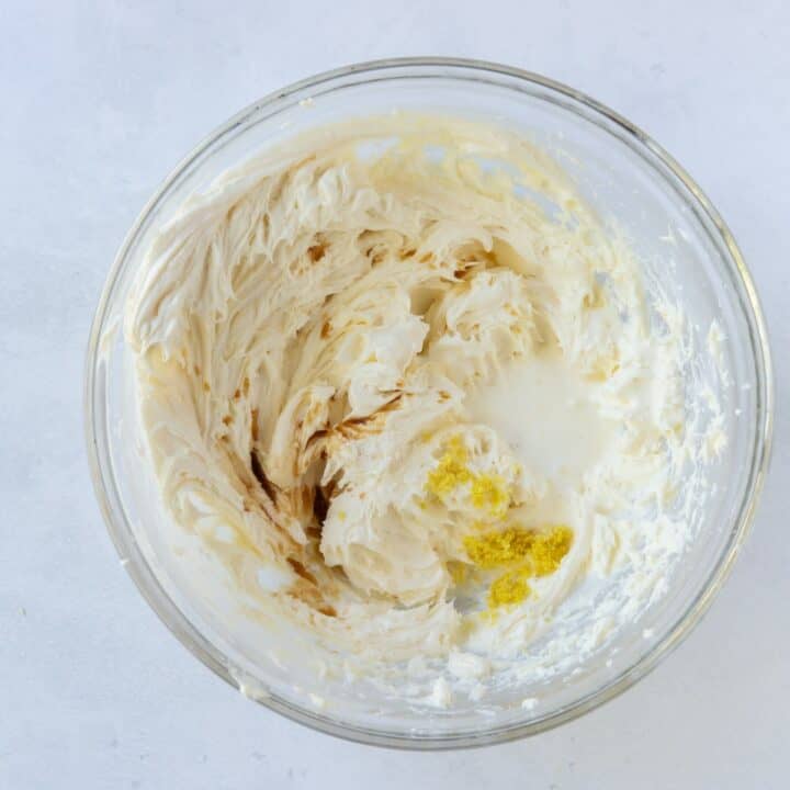 Glass bowl with all of the cream cheese frosting ingredients being mixed.