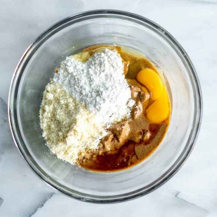 Glass bowl with all of the unmixed ingredients for keto almond butter cookies.
