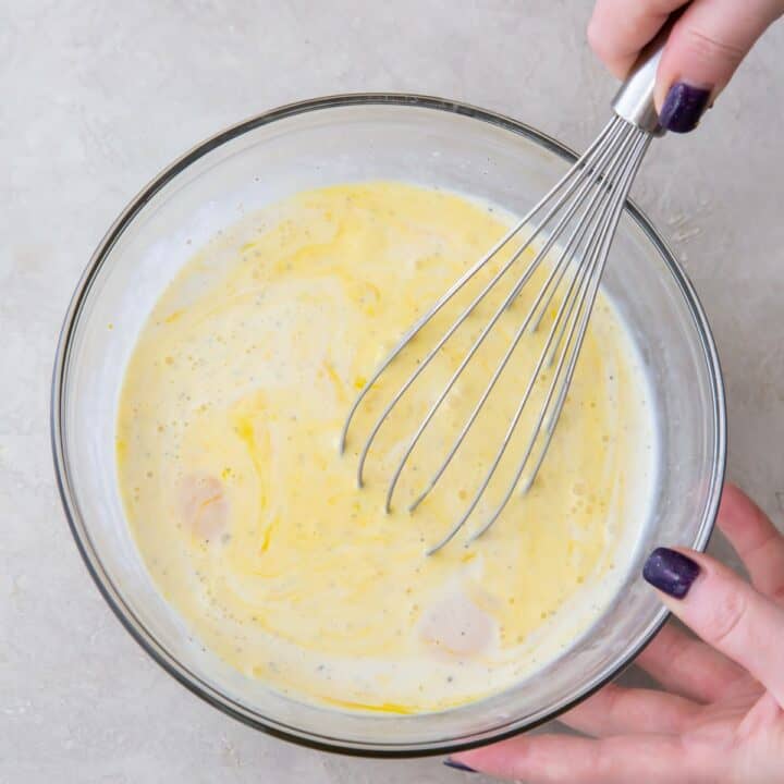 glass bowl with the wet ingredients for a keto quiche being whisked by a feminine hand.