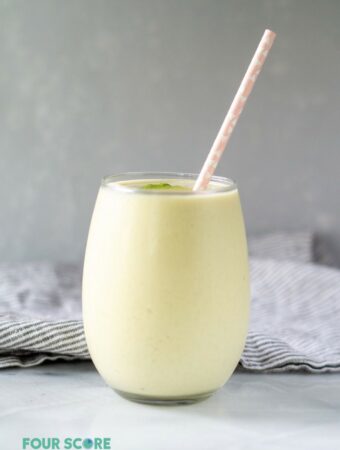 keto avocado smoothie in a glass with a straw.