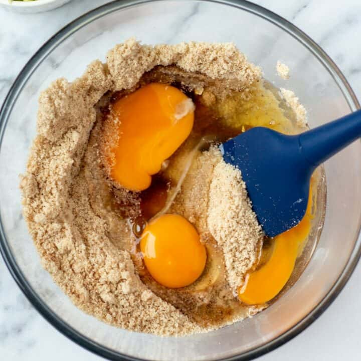 Eggs, oil, syrup and vanilla extract being added to the dry ingredients in a glass bowl.