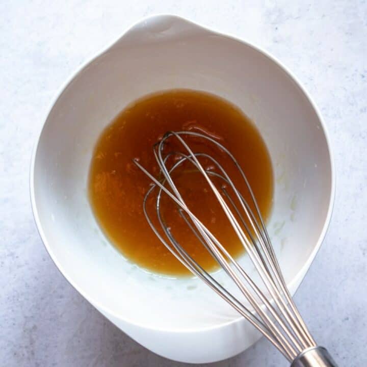 Bowl with the salad dressing ingredients being whisked.