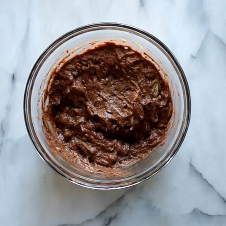 Glass bowl filled with the mixed thick muffin batter.