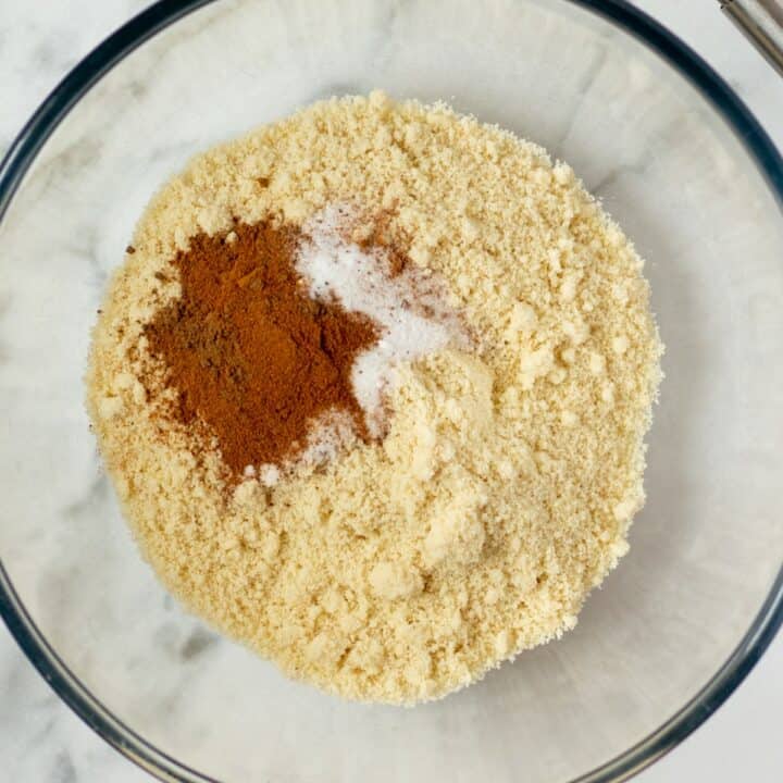 Glass mixing bowl with the dry ingredients. Almond flour, salt, baking soda, cinnamon and nutmeg.